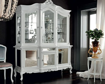 White ornate display cabinet made of mahogany wood and tempered glass. Hutch style with mirrored panel doors below the display shelves.