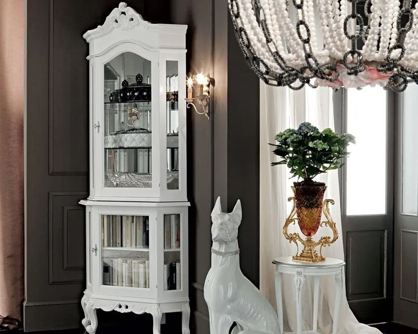 White corner display cabinet in a room with a chandelier, plant, and decorative items.