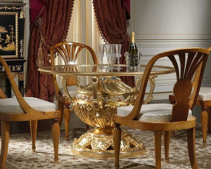 Decorative gold table with glass top and wooden chairs in an elegant room.